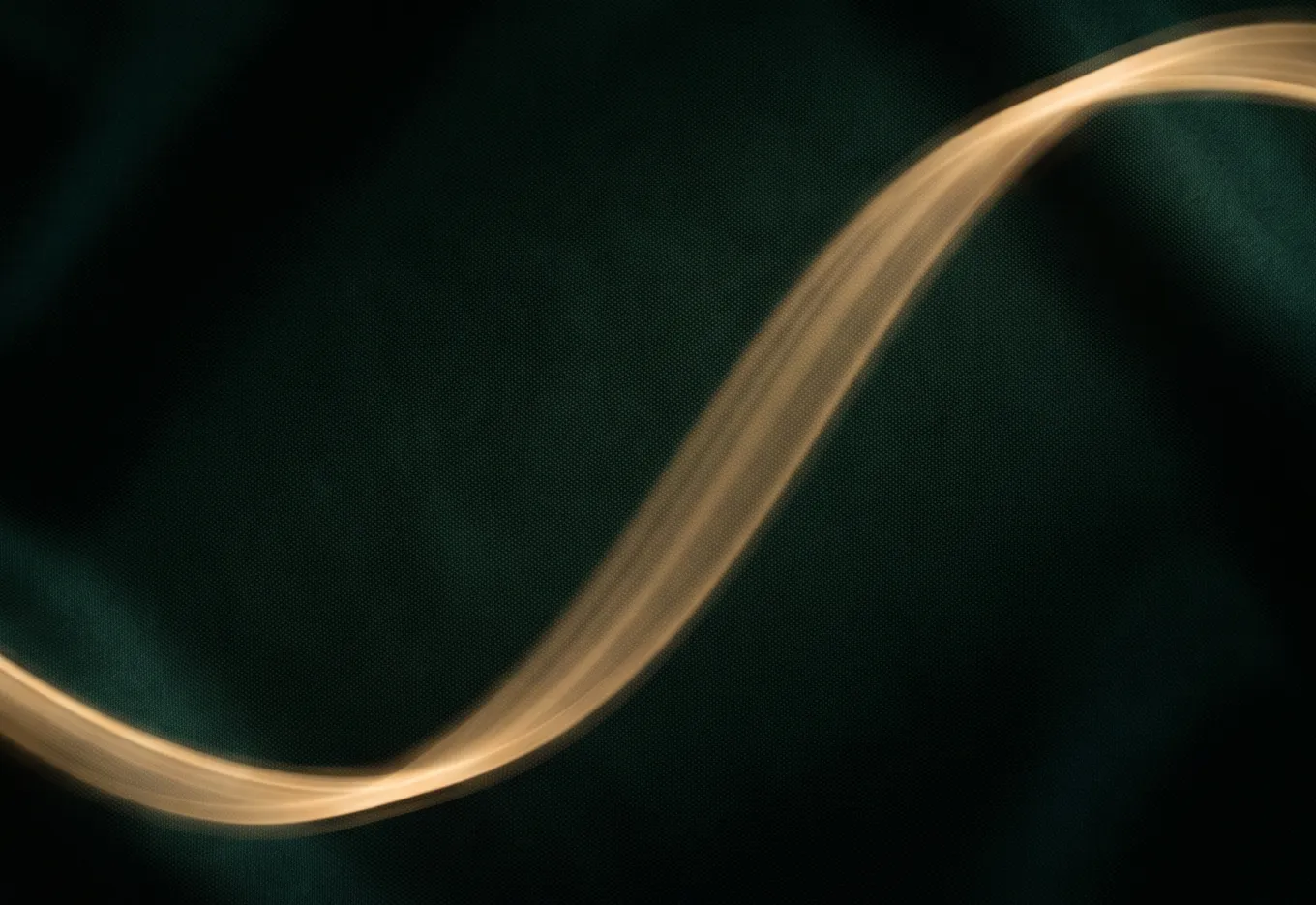 A single ribbon of golden light curving upward across deep green silk.