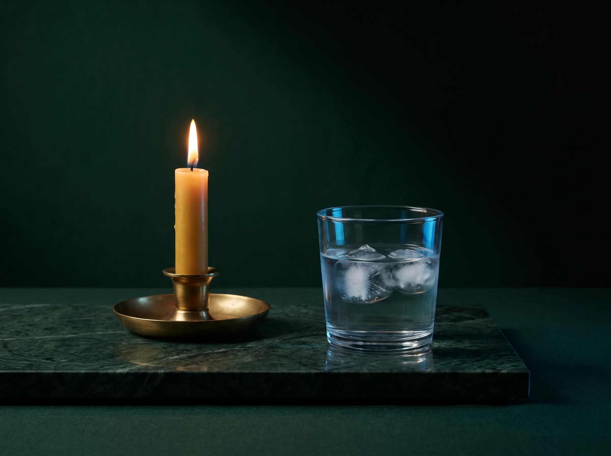 A lit candle and a glass of ice water side by side on green marble — the hot brain and the cool brain.